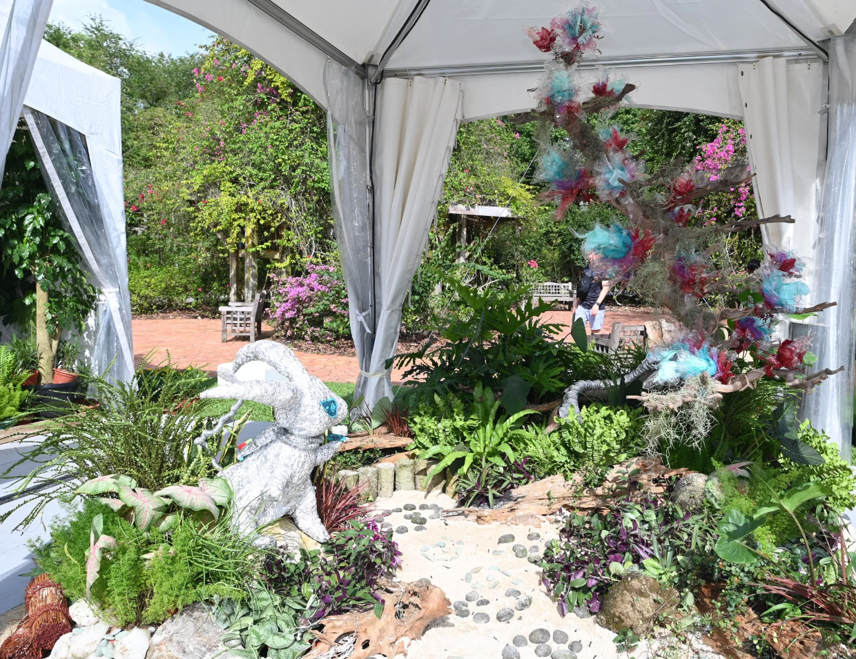 A landscape display under an outdoor tent with sandy footpath 
